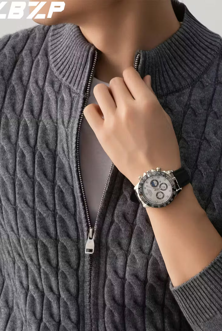 Person wearing a gray cable knit sweater with a watch on a neutral background