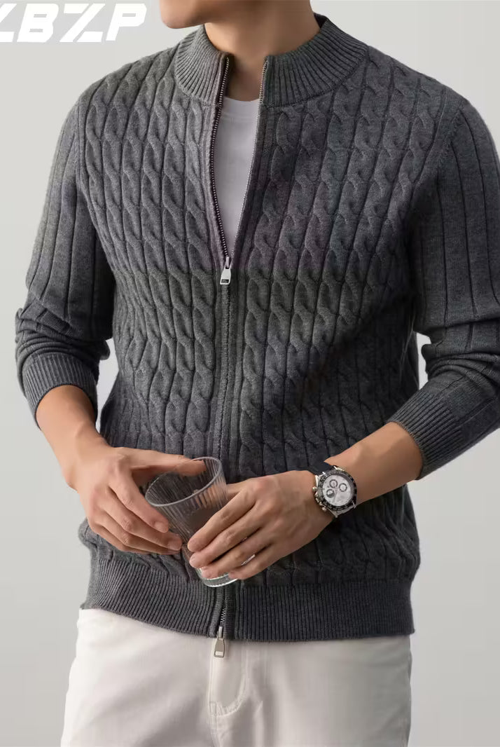 Person wearing a gray cable knit sweater with a zipper on a plain background
