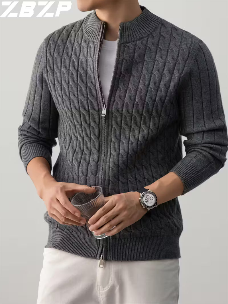 Person wearing a gray cable knit sweater with a zipper on a plain background