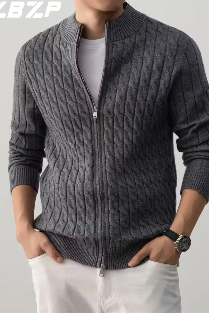 Person wearing a gray cable knit sweater with a zipper on a plain background