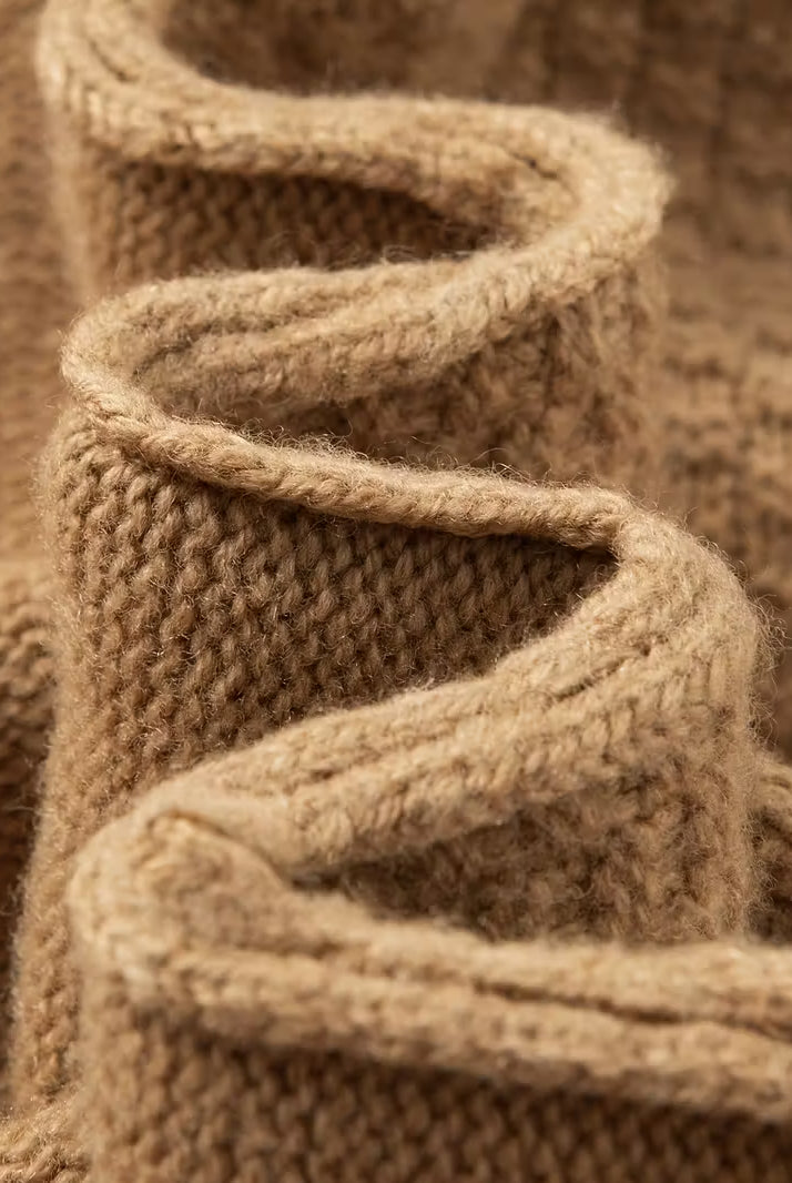 Close-up of a knitted brown fabric with a textured pattern.