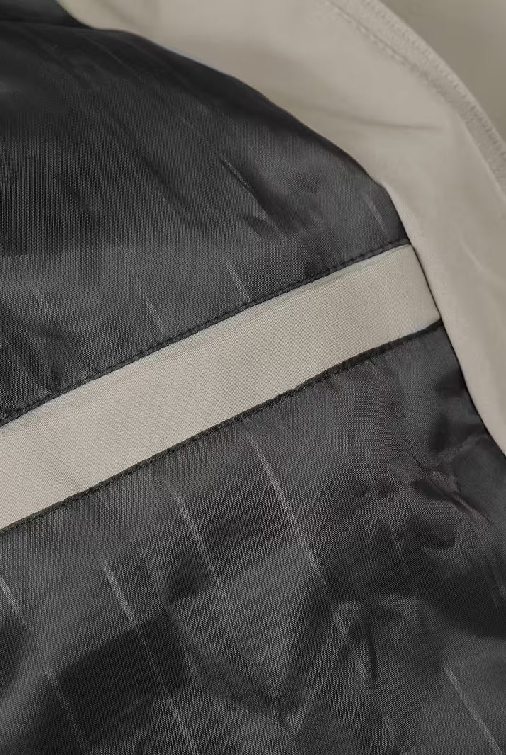 Close-up of a black and beige jacket with reflective striping.