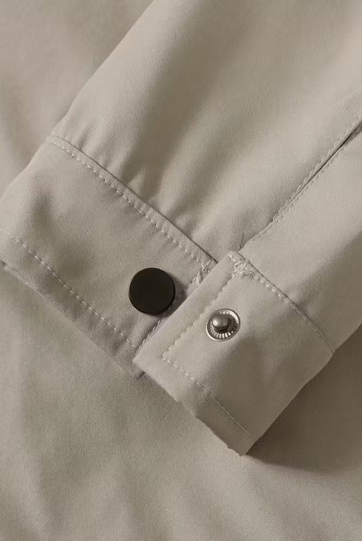 Close-up of a beige shirt with buttons on a neutral background