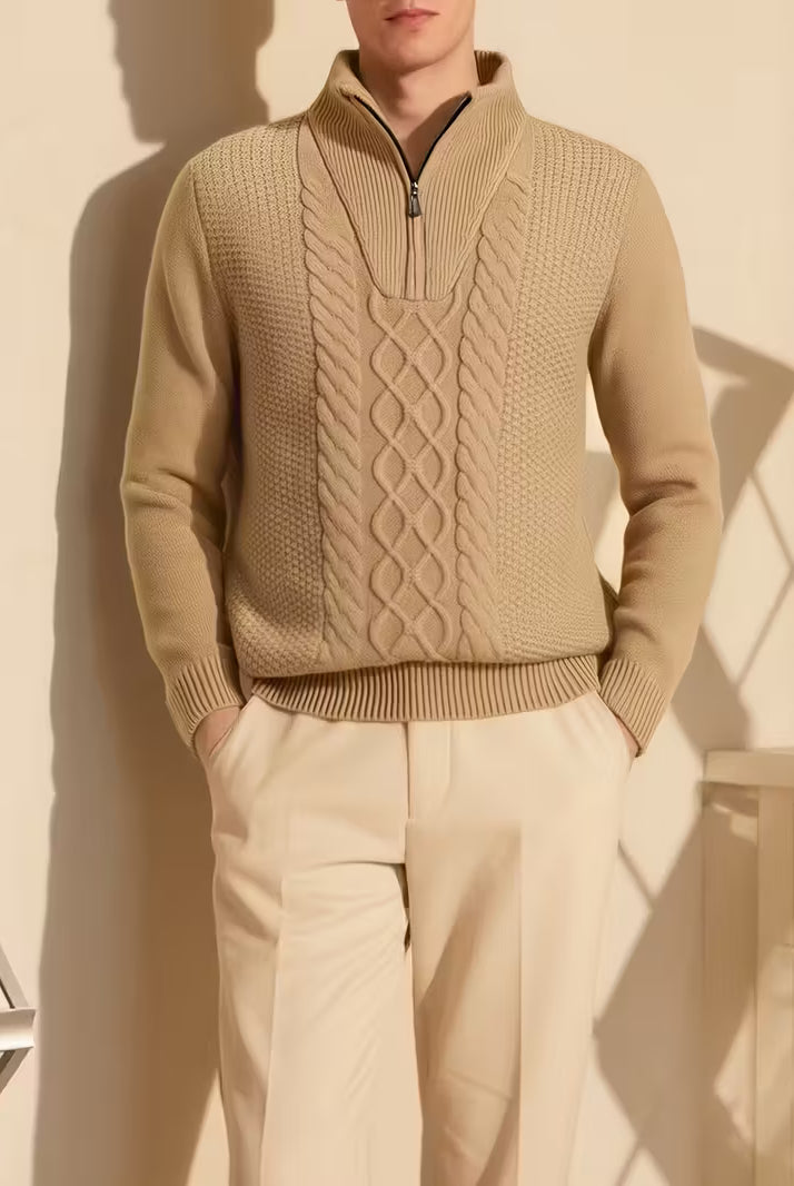 Person wearing a beige cable knit sweater and pants against a neutral background