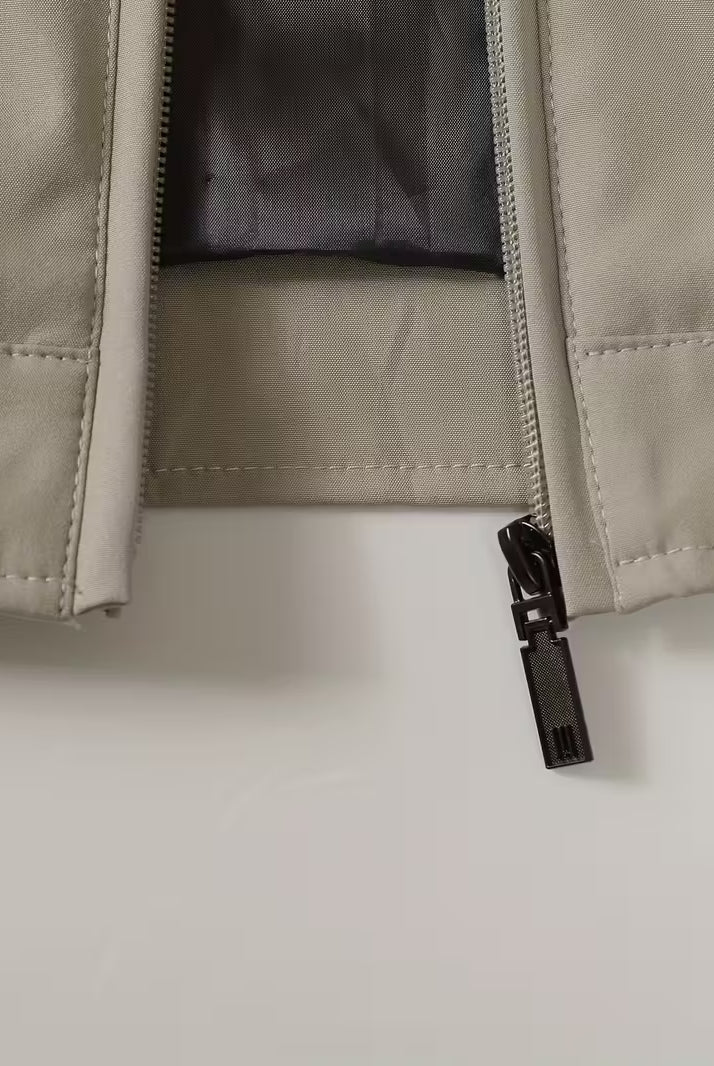 Close-up of a beige jacket with a black zipper on a light gray background