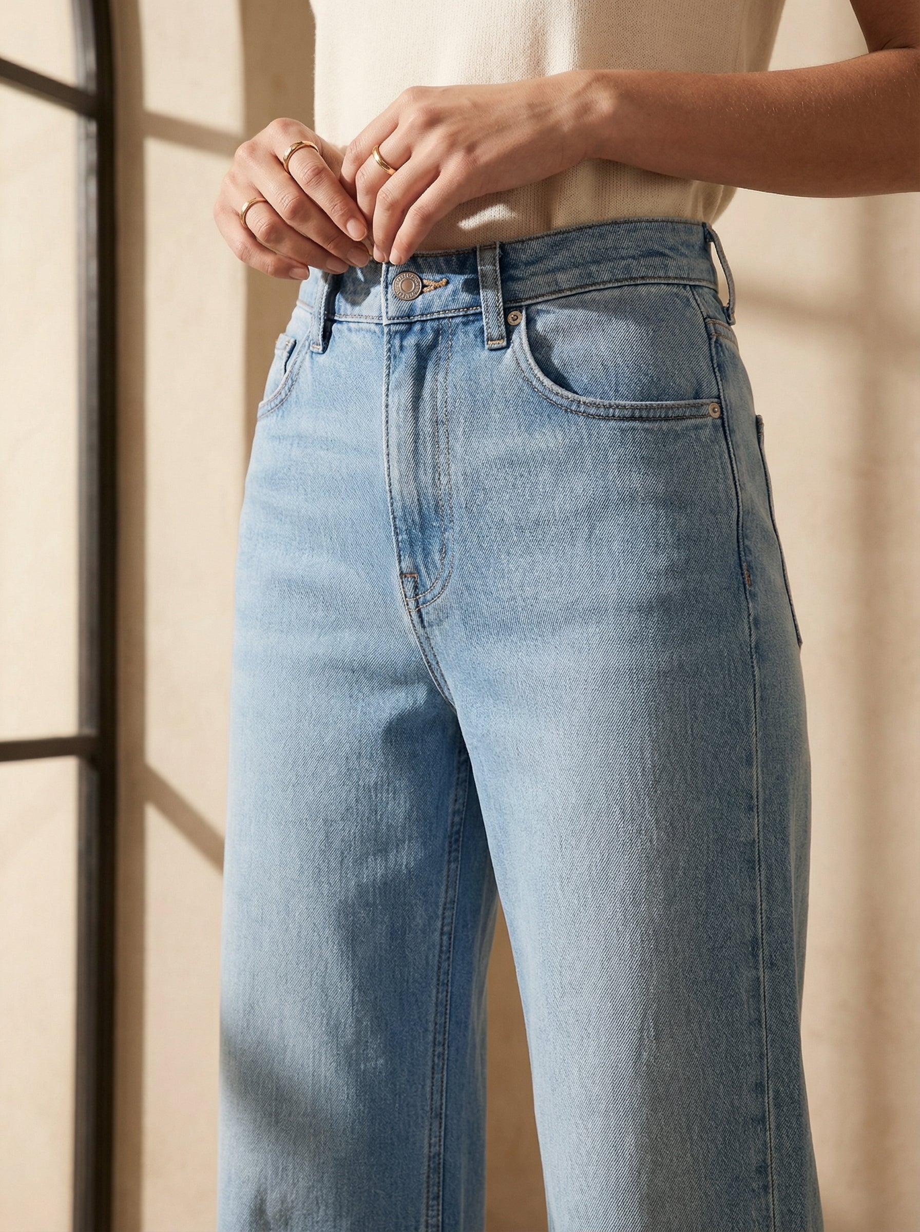 Person wearing light blue jeans with a neutral background