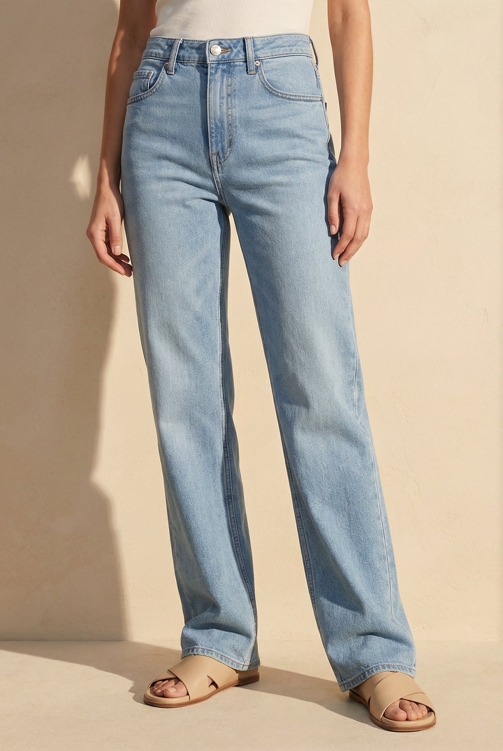 Light blue jeans worn by a person on a beige background