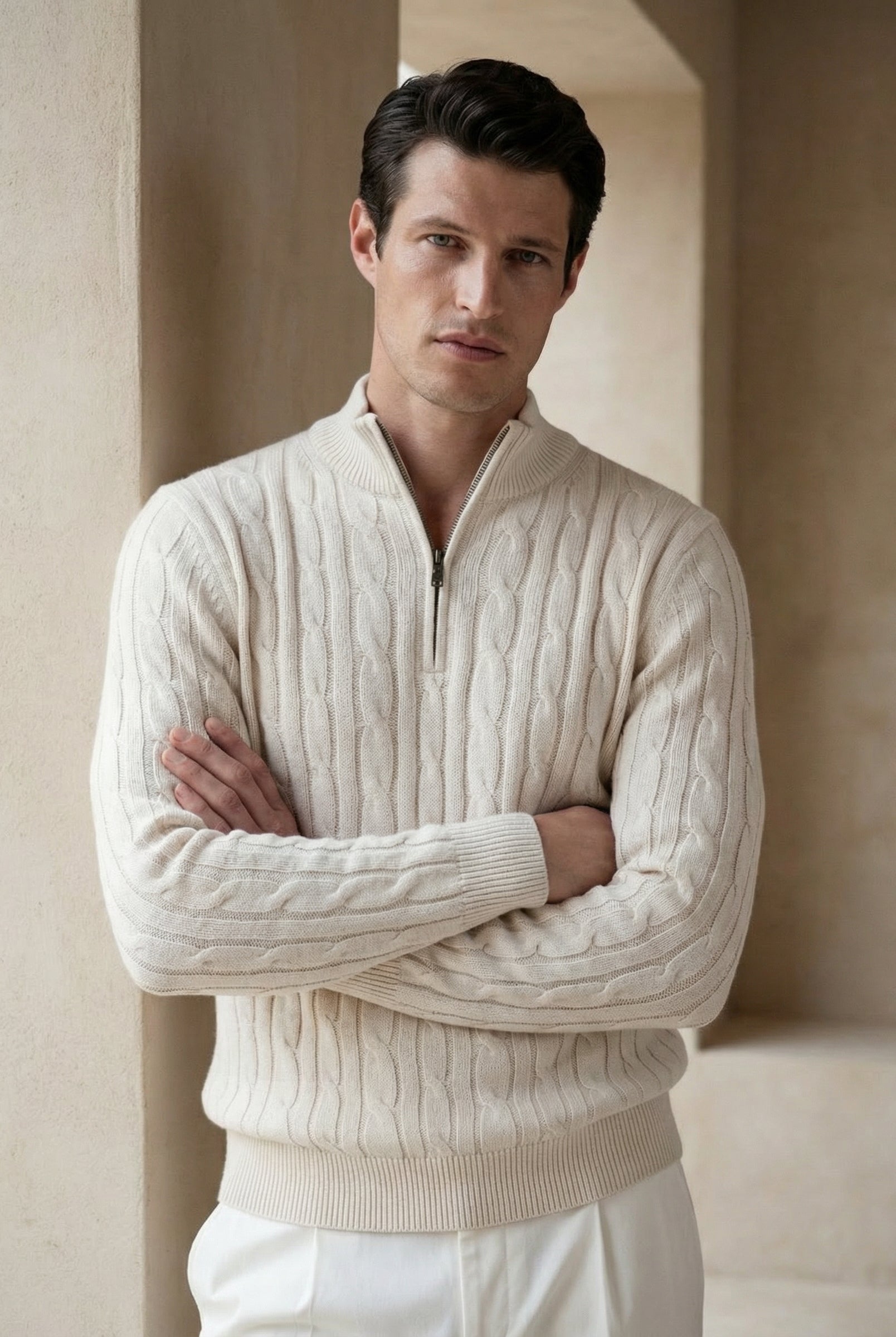 Man wearing a cream cable knit sweater with a quarter zip in a neutral setting