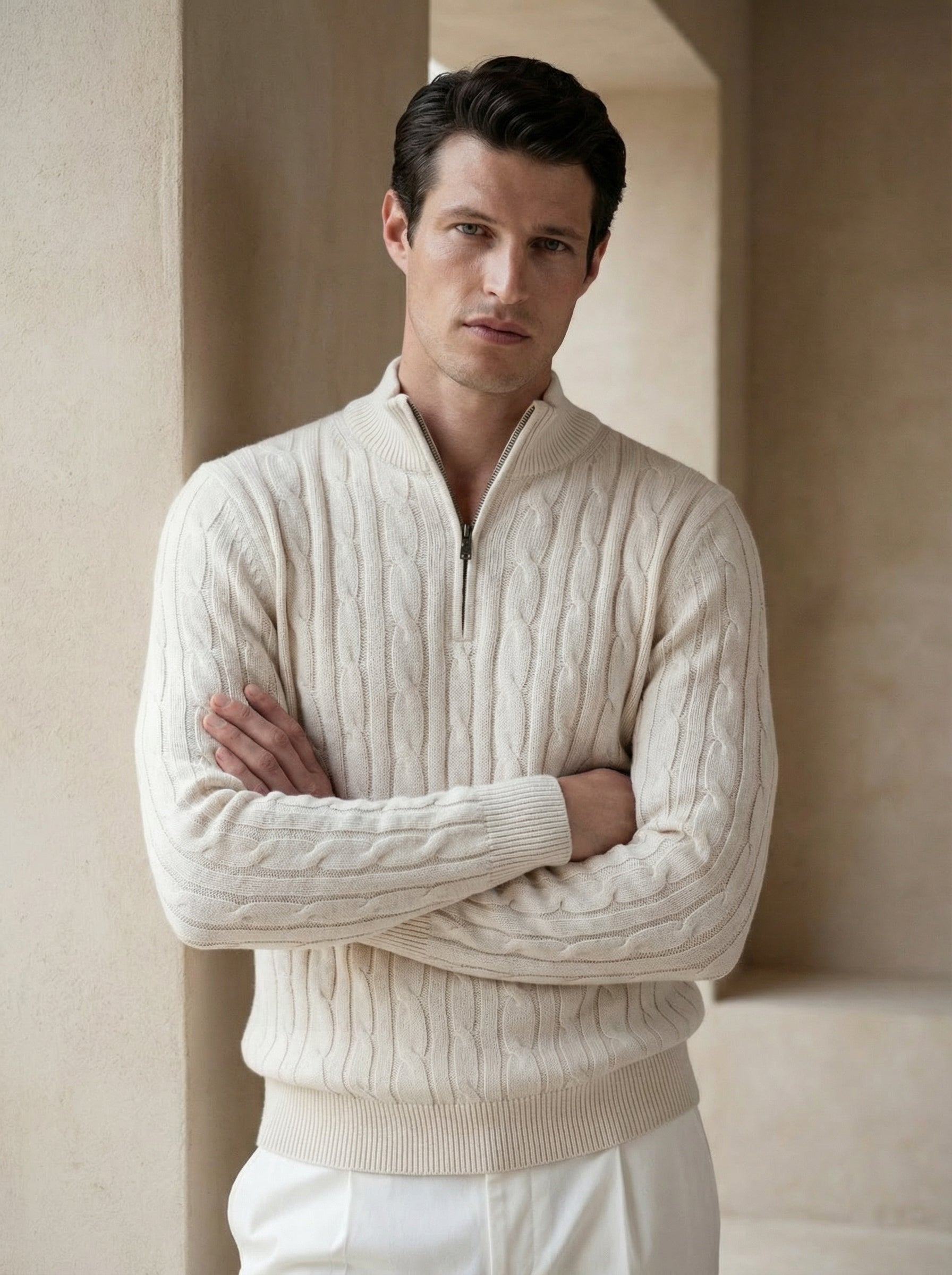 Man wearing a cream cable knit sweater with a quarter zip in a neutral setting