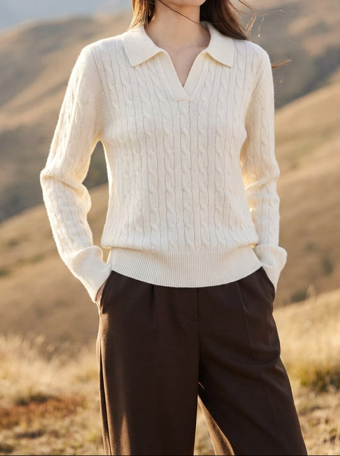 Woman in a cream sweater and brown pants standing in a mountainous landscape
