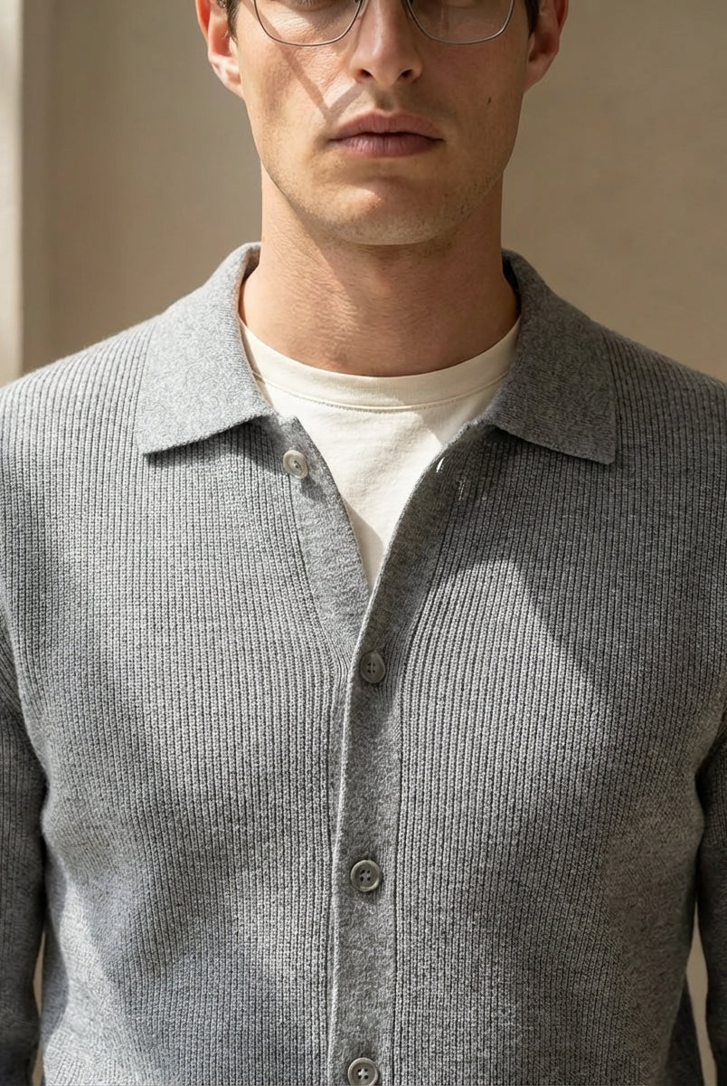 Man wearing a gray textured shirt over a white shirt against a neutral background