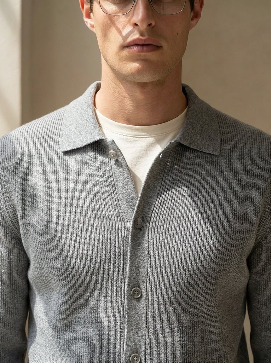 Man wearing a gray textured shirt over a white shirt against a neutral background