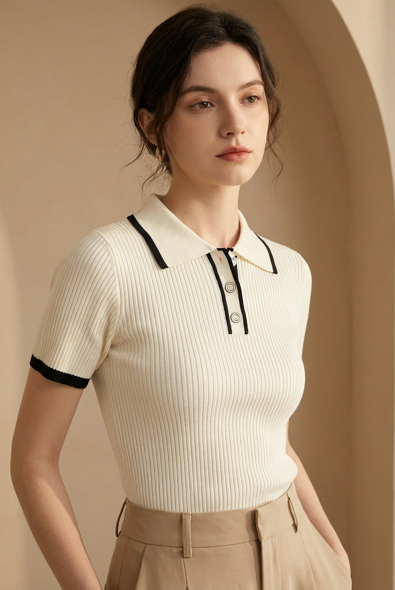 Woman wearing a white ribbed polo shirt with black trim against a beige background
