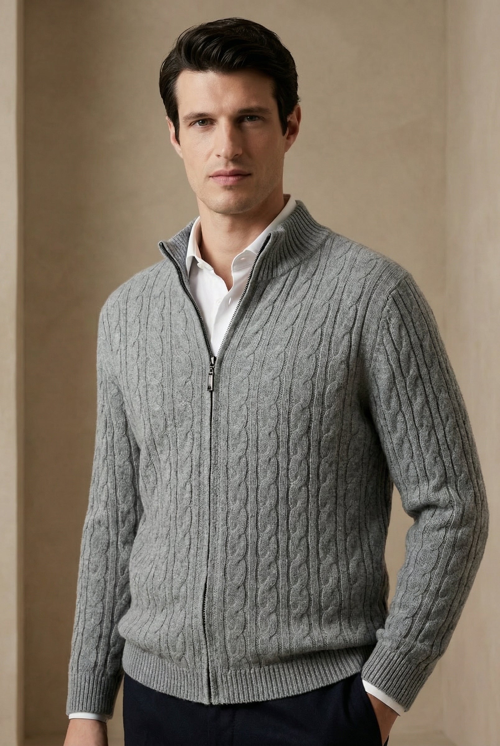Man wearing a gray cable knit sweater against a beige background