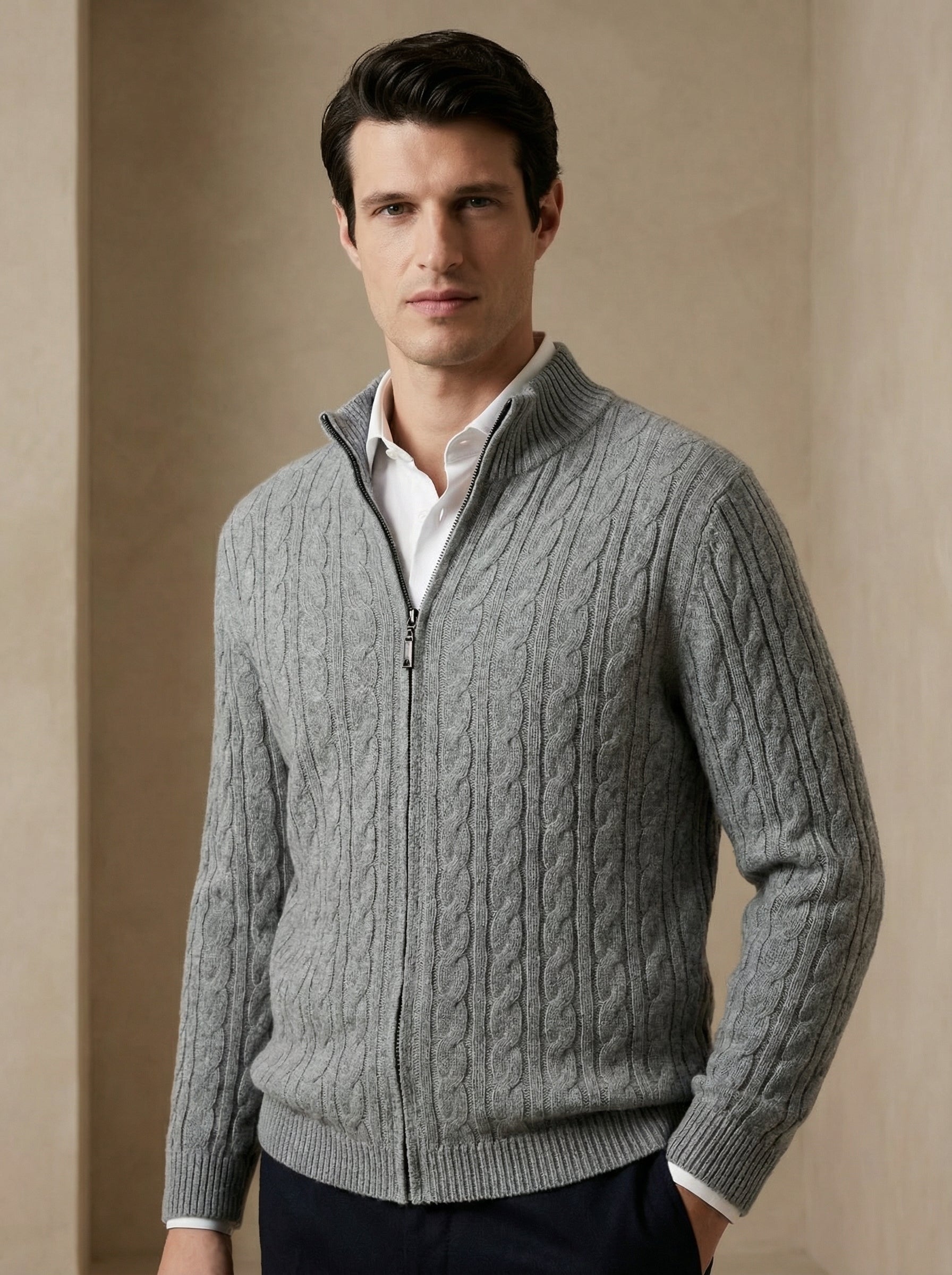 Man wearing a gray cable knit sweater against a beige background
