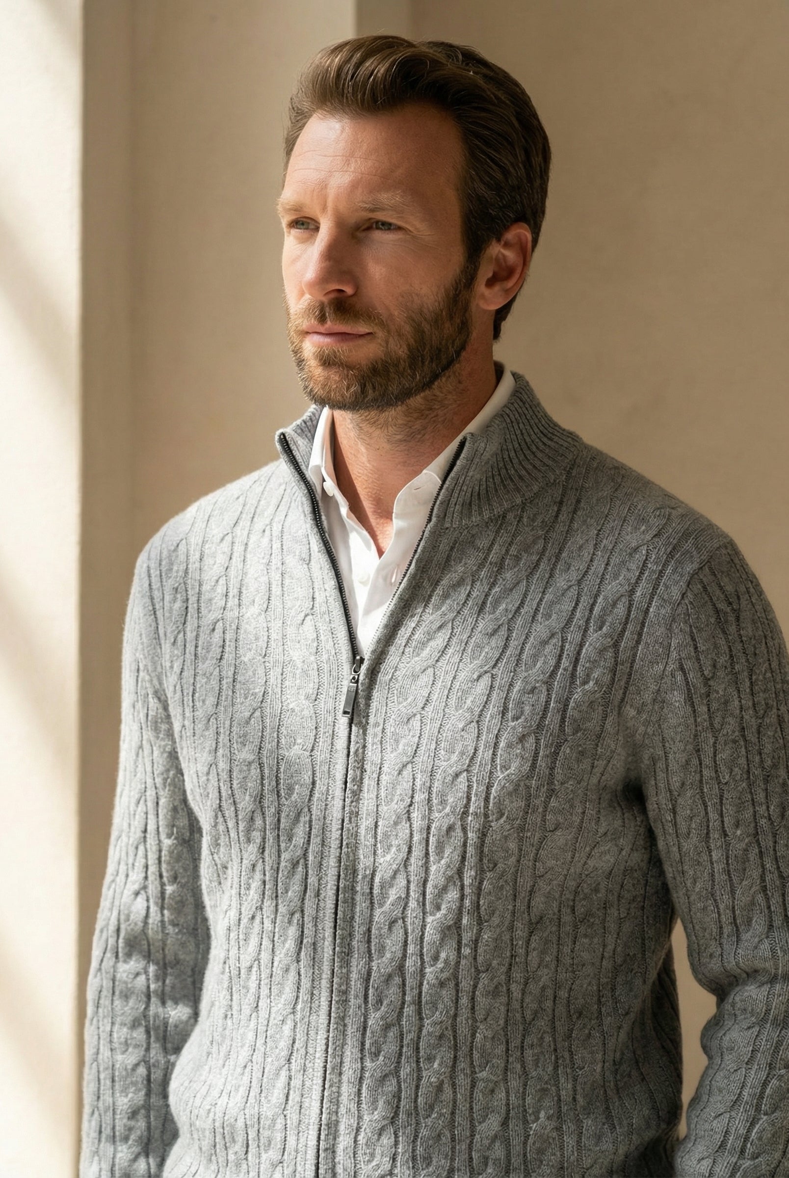 Man wearing a gray cable knit sweater against a neutral background