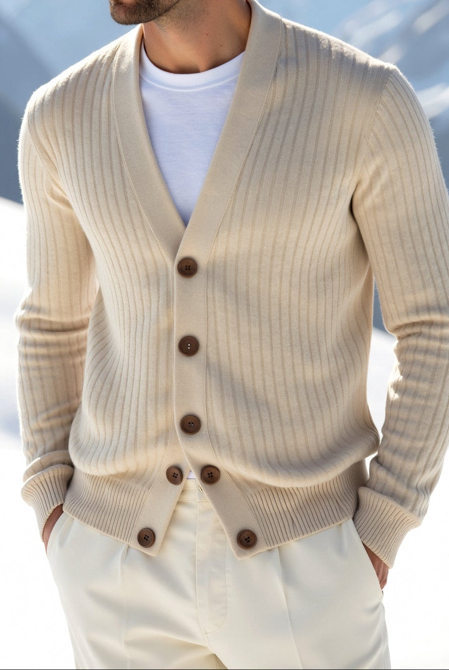 Man wearing a beige cardigan in a snowy mountain landscape