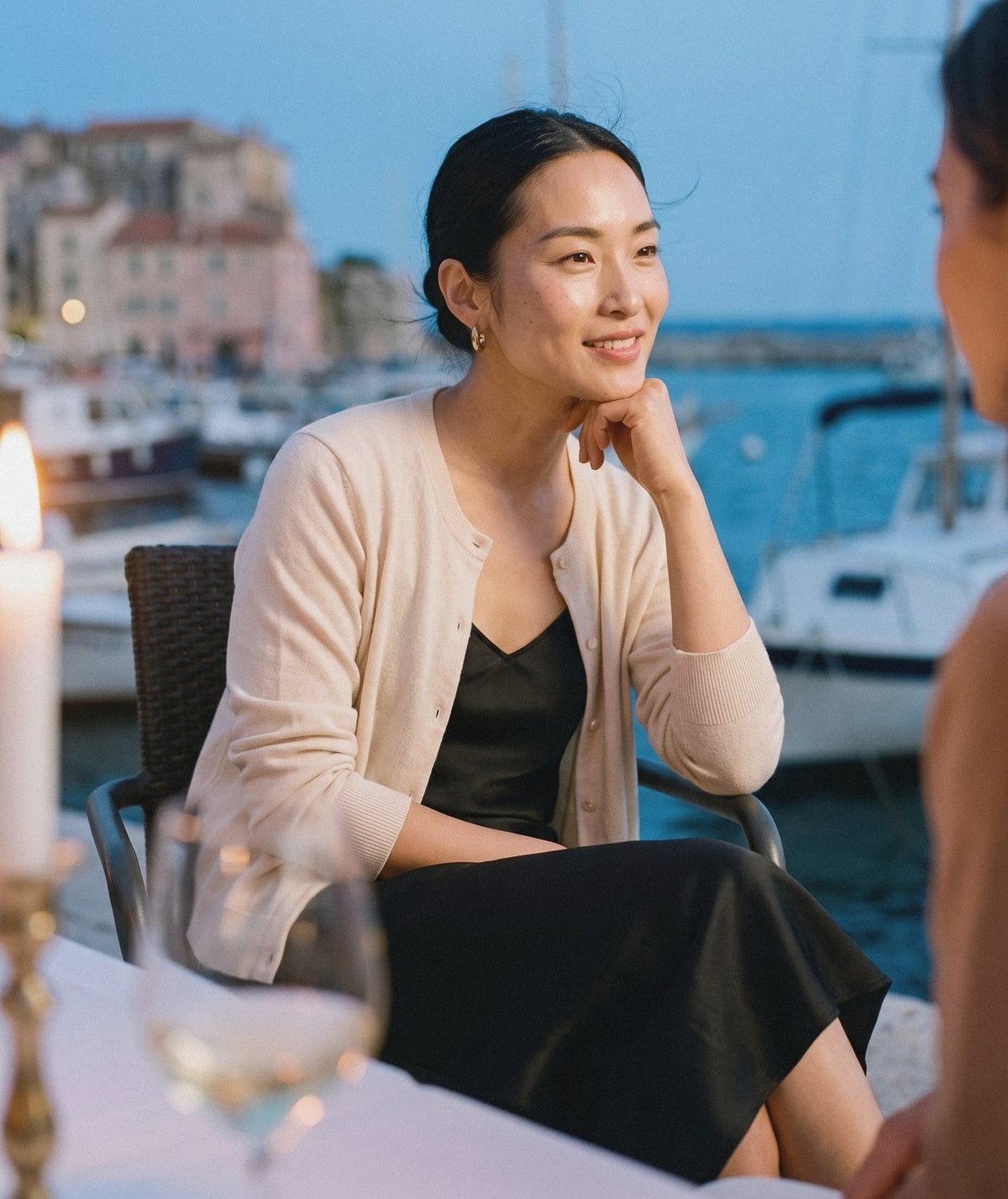 Woman in a cream cardigan and silk skirt at an evening dinner