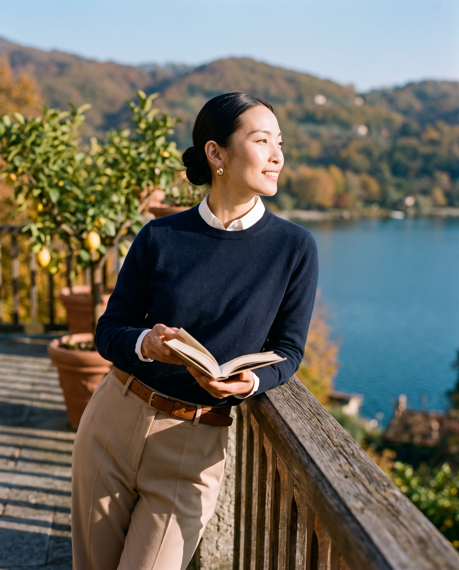 Woman in a navy crew neck sweater over a white shirt on a lake terrace