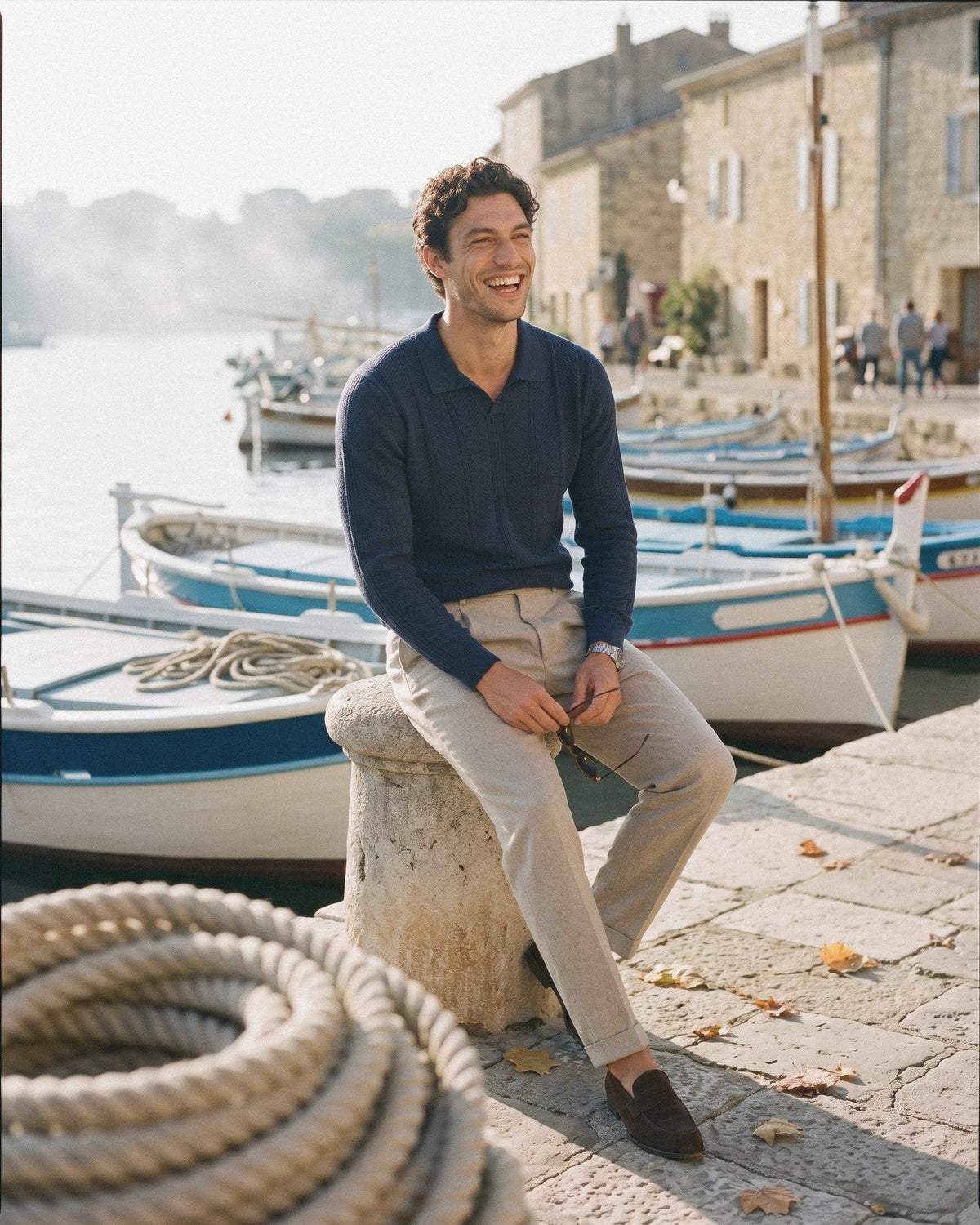 Man in a navy long-sleeve knitted polo and beige trousers on a harbour quay – BLENIN men's knitted polos