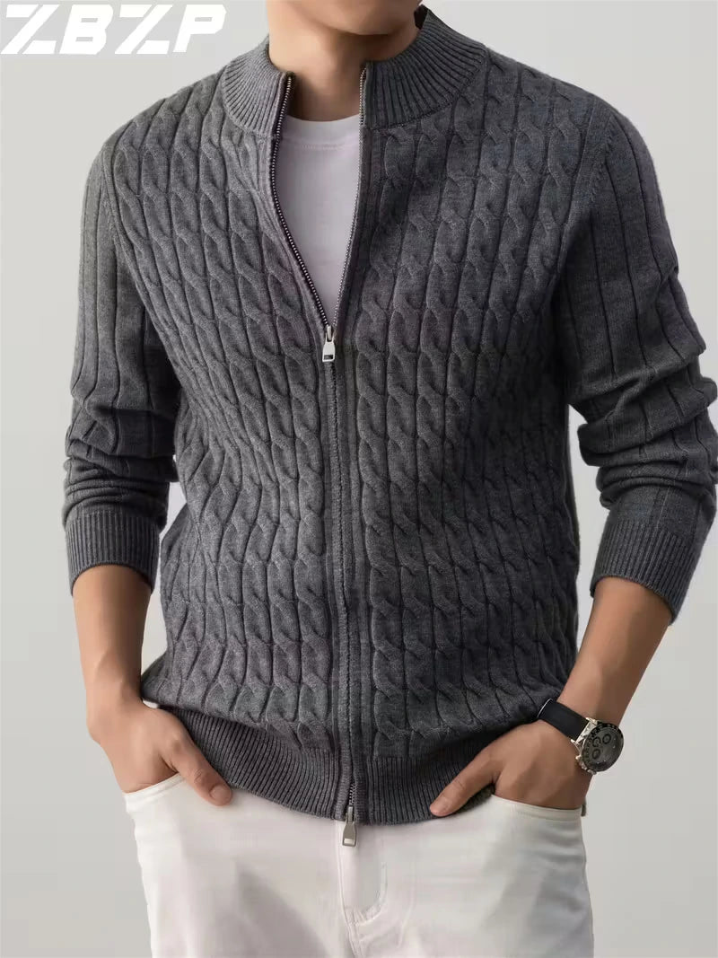 Person wearing a gray cable knit sweater with a zipper on a plain background