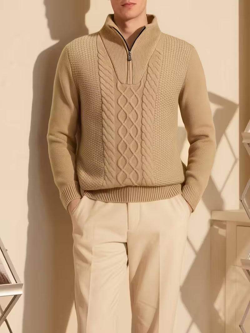 Person wearing a beige cable knit sweater and pants against a neutral background
