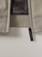 Close-up of a beige jacket with a black zipper on a light gray background