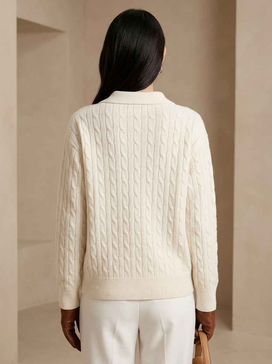 Person wearing a cream cable knit sweater and white pants against a beige background