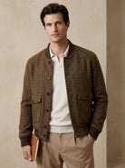 Man wearing a brown checkered jacket over a white shirt with a beige background