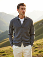 Man wearing a gray cardigan over a white shirt in a mountainous landscape