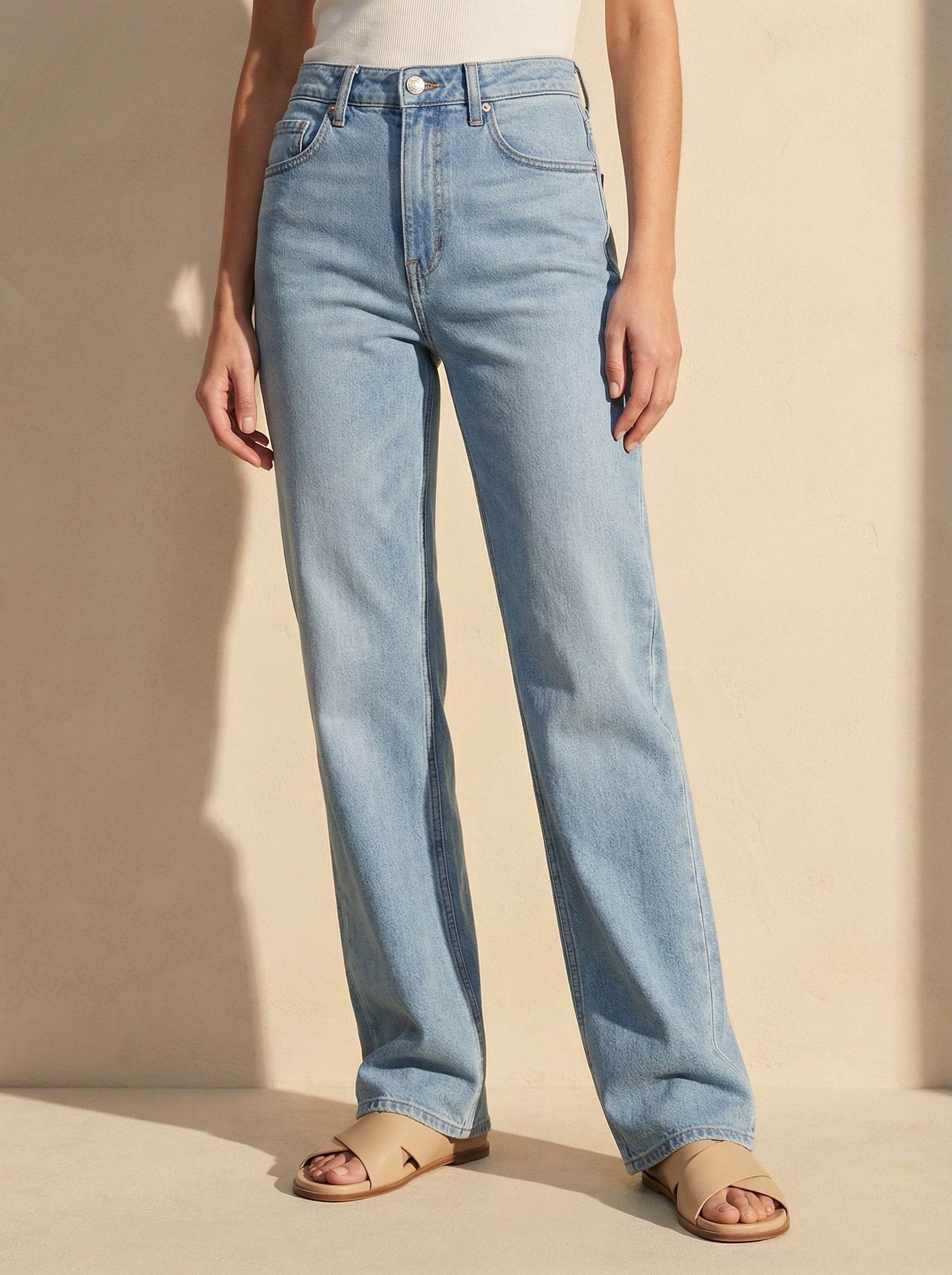 Light blue jeans worn by a person on a beige background