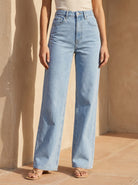 Light blue jeans worn by a person against a beige wall.