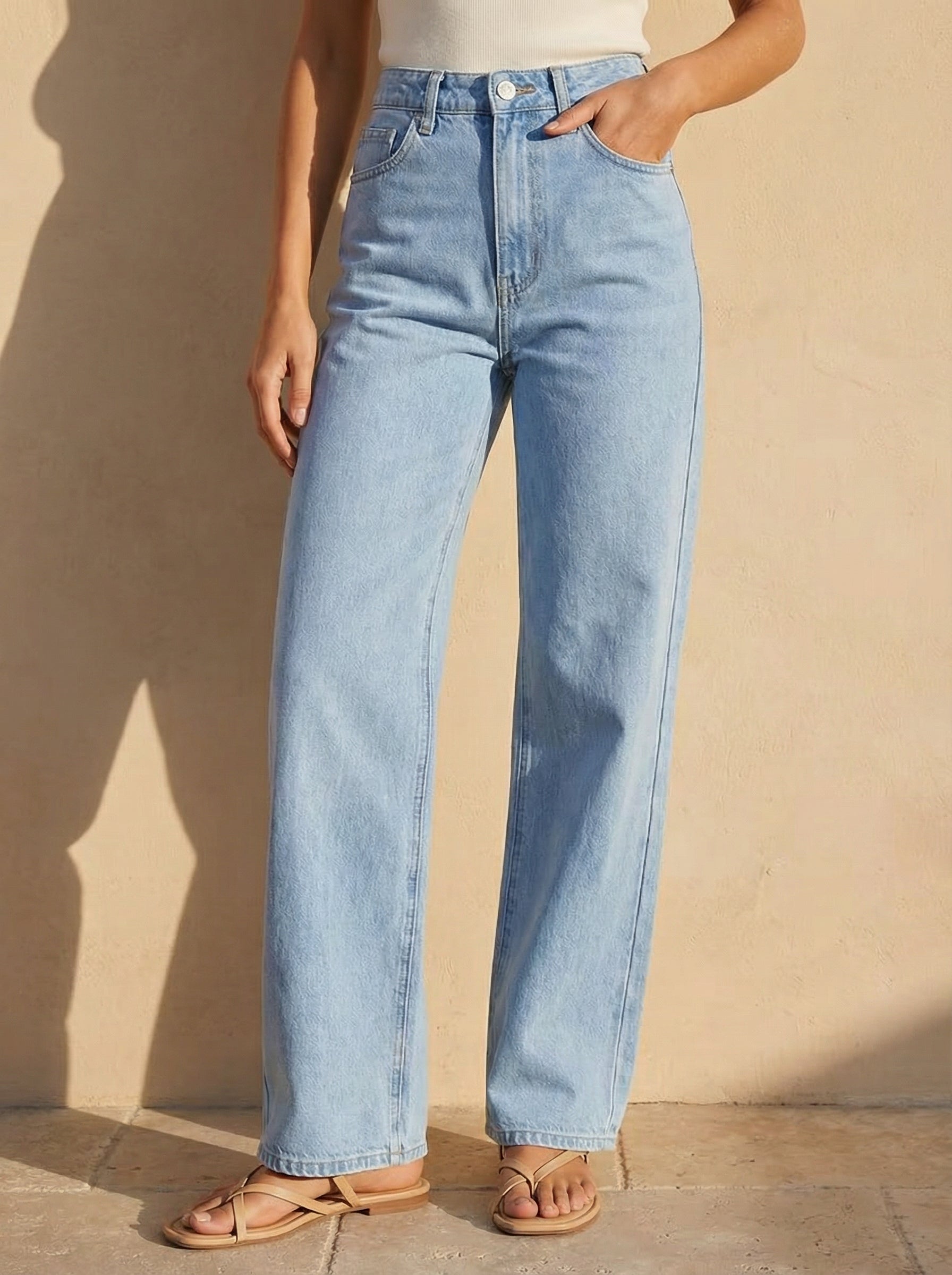 Light blue jeans worn by a person against a beige wall.