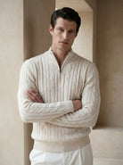 Man wearing a cream cable knit sweater with a quarter zip in a neutral setting