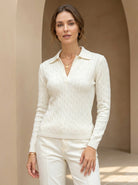 Woman wearing a white cable knit sweater and pants in a neutral setting