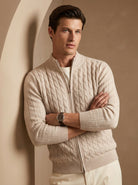 Man wearing a beige cable knit sweater against a beige wall