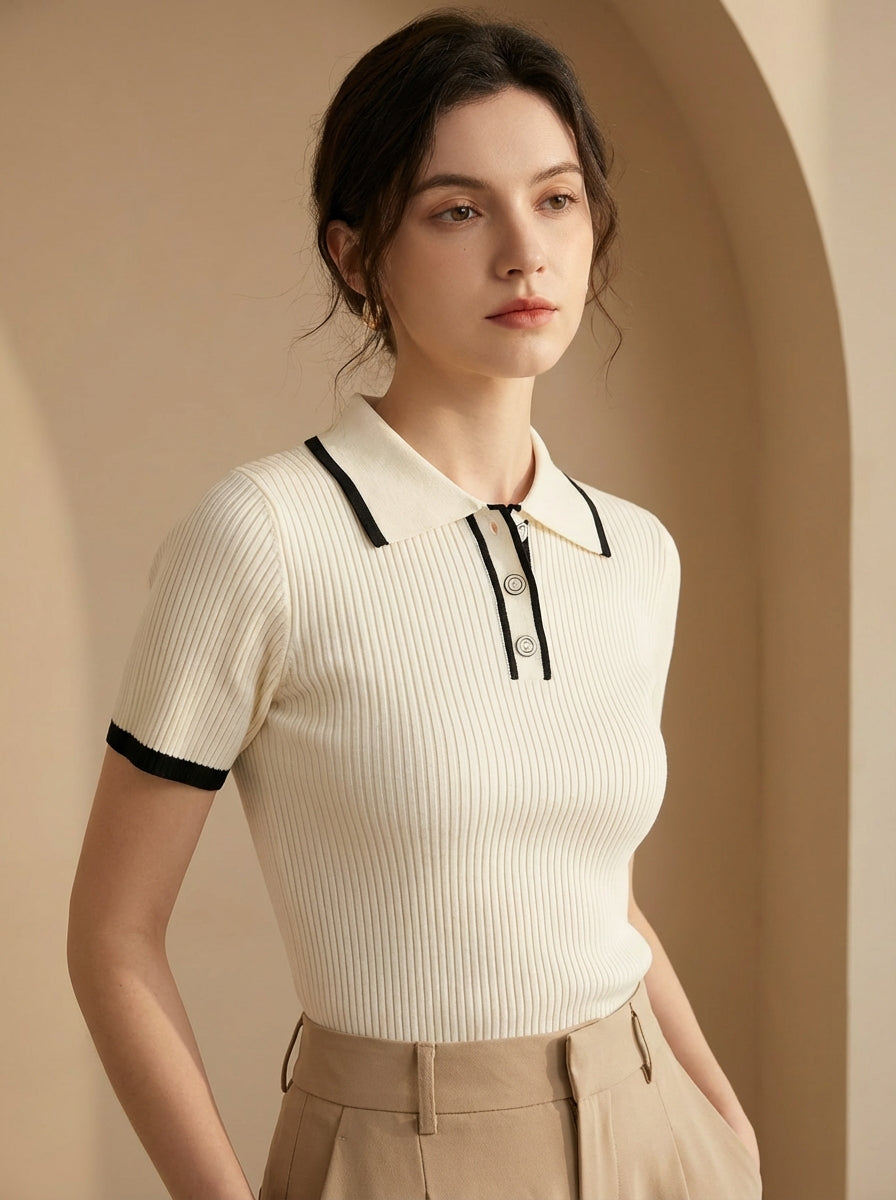 Woman wearing a white ribbed polo shirt with black trim against a beige background