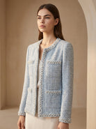 Woman wearing a light blue textured jacket with pearl embellishments against a beige background