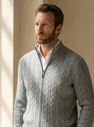 Man wearing a gray cable knit sweater against a neutral background