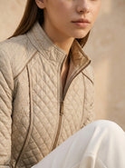 Person wearing a beige quilted jacket with a blurred background