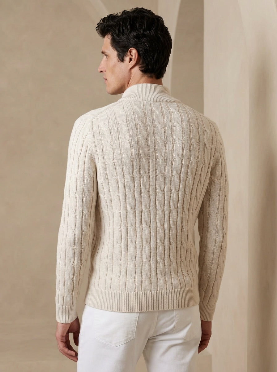 Man wearing a beige cable knit sweater against a beige wall