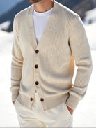 Man wearing a beige cardigan in a snowy mountain landscape