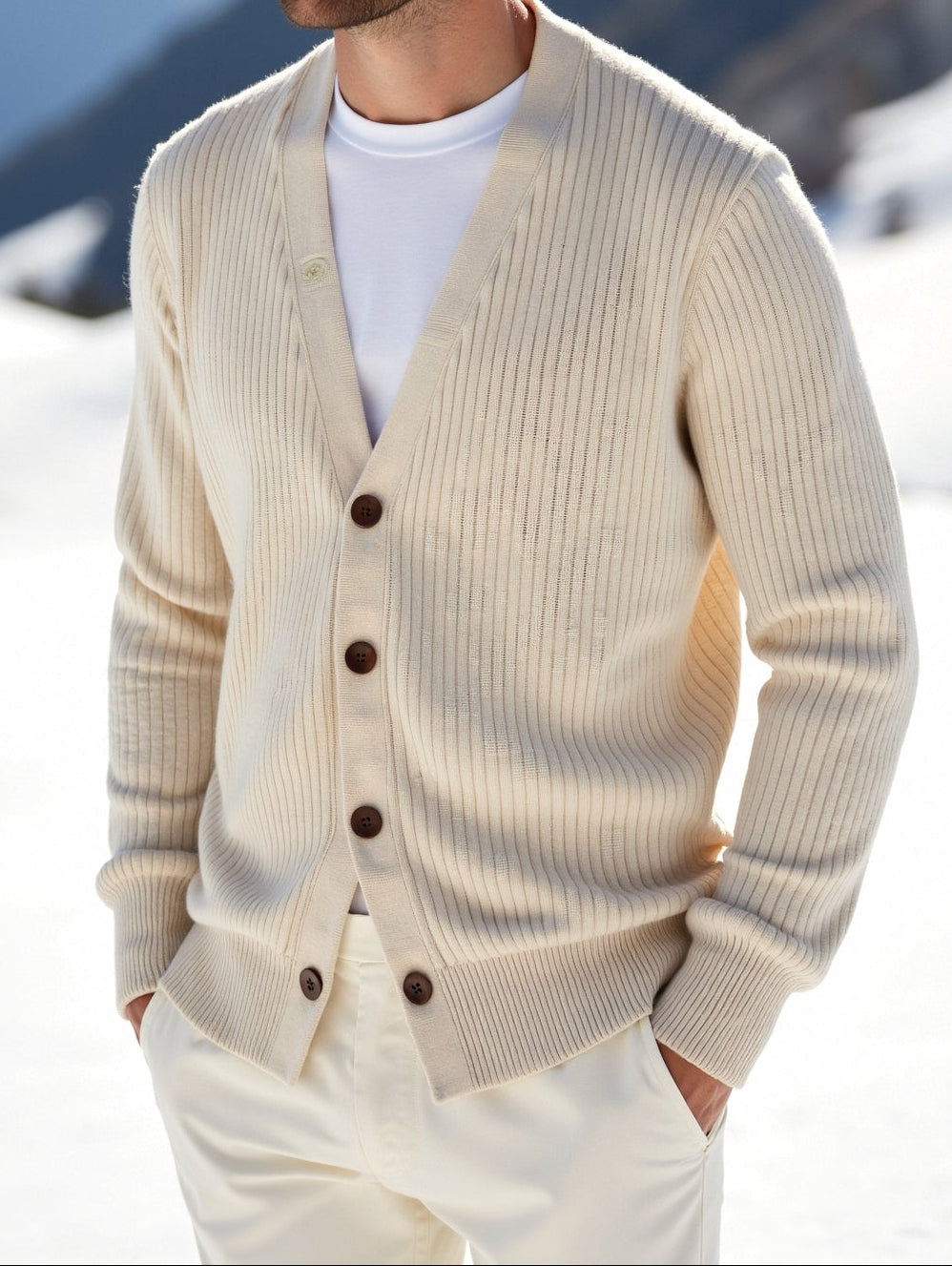 Man wearing a beige cardigan in a snowy mountain landscape