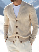 Man wearing a beige cardigan in a snowy mountain landscape